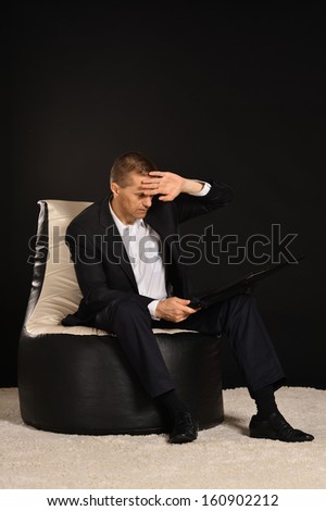 Portrait of serious businessman on black background with laptop