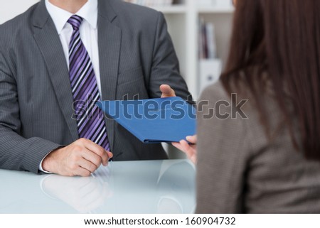 Employment interview with a close up view of a female applicant handing over a file containing her curriculum vitae to the businessman conducting the interview Royalty-Free Stock Photo #160904732