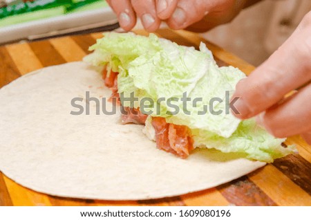 process of cooking tortilla rolls of salmon, tender cheese, lettuce, fresh cucumber close-up