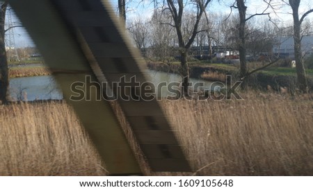 Travelling with train through Netherlands and making consecutive pictures from passenger's seat through window.