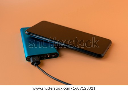 Power bank for charging mobile devices and devices. Blue smartphone charger with power bank. External battery for wireless headphones and speakers