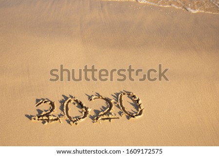 2020 summer beach holiday season written on golden sand - new season lettering on sand - numbers 2020 year travel vacation sandy yellow