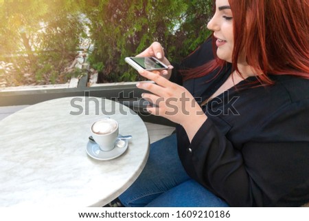 Happy overweight woman taking photo a cup of coffee for social media. Young plus size female model smiling and taking picture her business lunch. Concept of social life. Soft selective focus.
