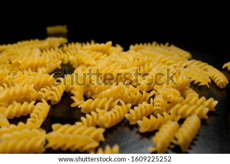 A contrasting photo of fussli macaroni scattered on a black background. Place for text.