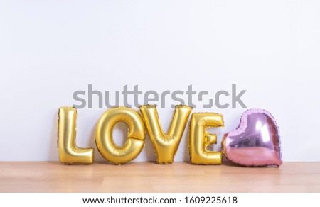 Valentine's day, Mother's day design concept - Beautiful balloon with word love shape on a light wooden floor and white wall background, close up.