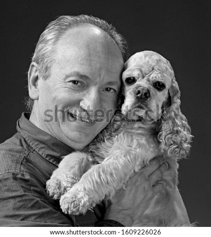 Smiling old man with a young dog posing in studio  on a grey background
