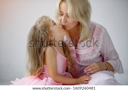 Beautiful woman with child. Woman in a pink pajama. Child in a bedroom in a pink dress.