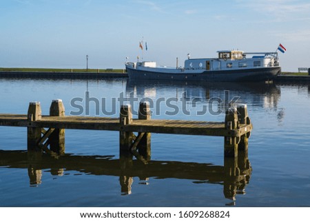 View of a wooden jetty in a harbor on the IJsselmeer / NL with a ship in the background
