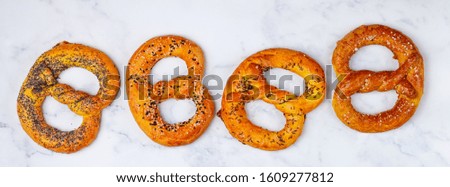 Pretzel. A set of different pretzels with black and white sesame, poppy seeds, cumin or caraway, large sea salt on a marble table. Sweet and salty appetizer. German (Bavarian) beer appetizer. banner