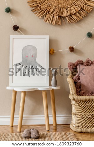 Stylish and modern scandinavian newborn baby interior with mock up photo frame on the small table. Toys, sofa with  pillow and hanging cotton colorful balls. Beige wall. Design home staging. Template