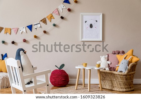 Stylish scandinavian interior of kid room with mock up poster frame, design furnitures, natural toys, hanging colorful flags, plush animal, child accessories and teddy bears. Modern home decor.