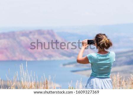 Woman taking picture of Sheep Creek Overlook in Manila, Utah near Flaming Gorge National Park with cloudy valley and river