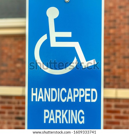 Square Close up of Handicapped Parking sign against blurred red brick wall of church