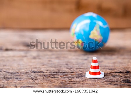 stop sign with traffic cone over blurred globe on wooden floor.