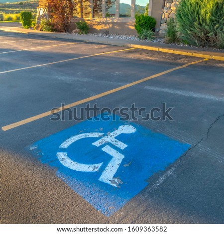 Square Handicapped parking space at a parking lot outside a building on a sunny day