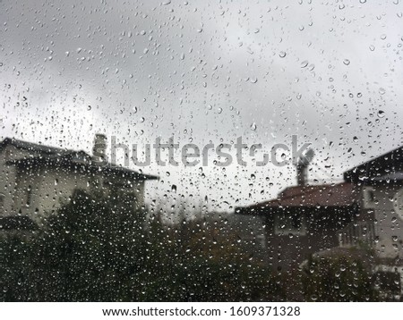 Rain drops on window glass. Green textured glass surface. Weather outside, poor conditions drab dreary bleak cold.