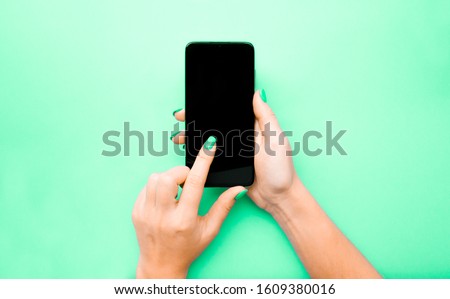 The layout of the phone. The girl flips through the pages. Swipe your finger across the screen. Background mint color under the color of nails. Pantone 2020. Neo mint color. Flat lay.