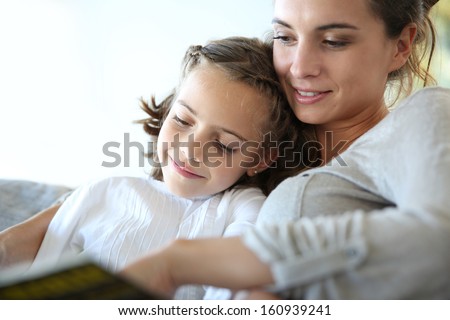 Mom with little girl reading book in sofa Royalty-Free Stock Photo #160939241