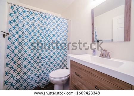 Small bathroom with patterned shower curtain in house Royalty-Free Stock Photo #1609423348