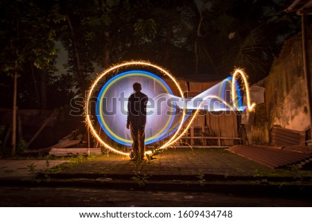 silhouette of Indonesian people standing alone isolated with white yellow and blue light painting as a backdrop