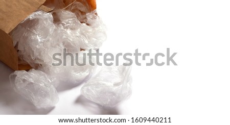 Transparent disposable plastic bags in a paper bag on a white background. planet pollution concept. Space for text