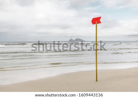 Red danger sign at the beach signaling to sunbathers rough sea or deep sea. Photo taken at Praia da Enseada beach - Guaruja SP Brazil.