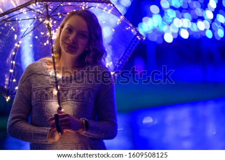 Woman or girl with umbrella with lights during the rain, lights and garlands. Rain atmosphere, art photo. Horizontal photo.