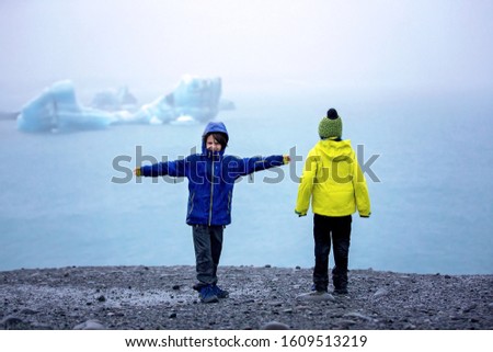 Child, taking picture at early evening on a rainy day at picturesque iceberg lagoon Jokursarlon in Iceland 