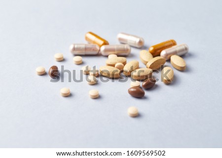 Multicolor vitamins and supplements on bright paper background. Concept for a healthy dietary supplementation. Close up. 