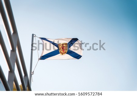 Flag of Nova Scotia on metal flag pole on blue sky background, Canada. The coat of arms of Nova Scotia, Canadian province
