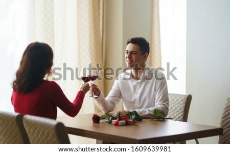 Couple clink glasses with red wine. Lovers give each other gifts. Lovely romantic dinner. Romance at restaurant for Valentine's Day concept. Relationship, surprise, Birthday concept.