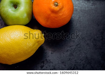 lemon, apple and orange close-up on a dark background