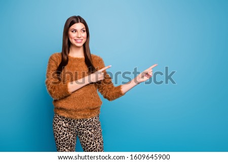 Portrait of positive cheerful girl point index finger copy space attention present ads promotion follow sales wear spring autumn outfit over blue color background