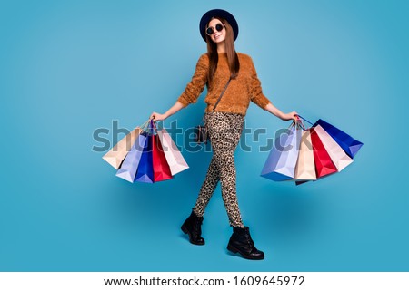 Full length photo of cheerful boutique client girl tourist travel autumn fall spring weekends hold bags wear brown sweater pants boots sunglass isolated  blue color background