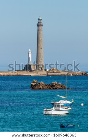 Lighthouse of the Virgin Island on the coast of French Brittany. The tallest lighthouse in Europe. Boats and a small islet in the foreground.