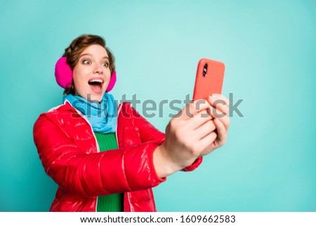 Photo of pretty crazy lady open mouth hold telephone good news check likes followers subscribers wear red coat scarf pink ear covers green jumper isolated teal color background