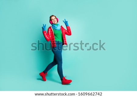 Full body photo of amazing lady enjoy winter day spend time walk street show v-sign symbols wear red overcoat blue scarf pink ear warmers pants boots isolated teal color background