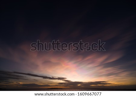 Beautiful nacreous clouds in rainbow colors over distant island a magic morning over Baltic Sea in northern Sweden.