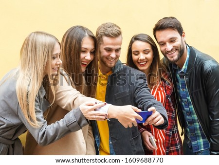 Young people using smartphones - Group of social media co workers having fun and takeing a selfie - Obsessed with online and shareing lifestyle moments -  Technology concept