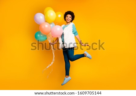 Fulll body photo of funny afro american girl hipster jump enjoy autumn holiday hold baloons  wear stylish white turquoise teal pullover blue trousers isolated bright color background