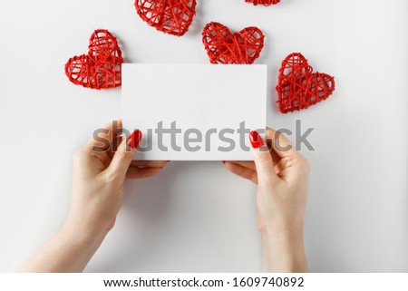 Blank card in hands on a white background - concept for design. Congratulatory letter on the background of hearts for Valentine's Day.