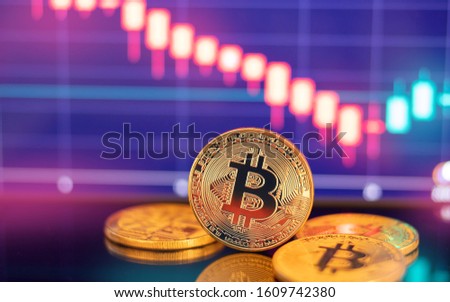 Gold Bitcoin crypto currency on background of dawn red chart diagram.