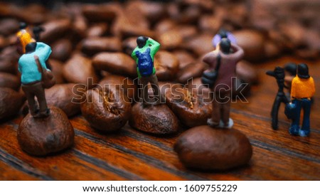miniature of group photographer taking picture around coffee beans on wooden table                                