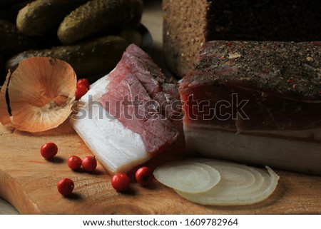 Slices of smoked ham with spices, pickled cucumbers and onion, close up.