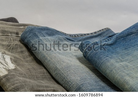 Closeup of three pairs of denim jeans on white background.