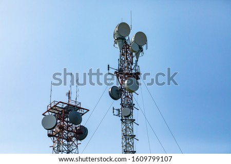 Telecommunication and mobile network infrastructure with two cell site towers side by side, housing antennas and Remote Radio Head, RRH, for greater coverage Royalty-Free Stock Photo #1609799107