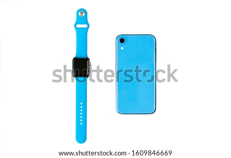 New modern gadgets, isolate devices: Smart Watch with blue sport band, blue cell mobile phone isolated on white background. Top view. Fitness smartwatches. Wearable technology concept.