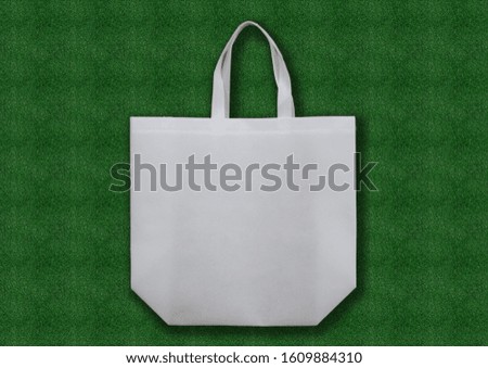 white Fabric ECO bag for groceries and shopping on a green grass background. An example of packaging that is healthy and environmentally friendly and then properly recycled.