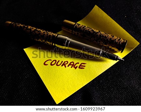 courage English words written on yellow paper slip on dark background 