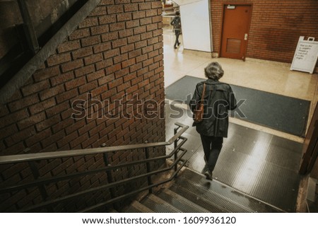 Woman going to the subway on stairs brick wall female with purse walking in the city